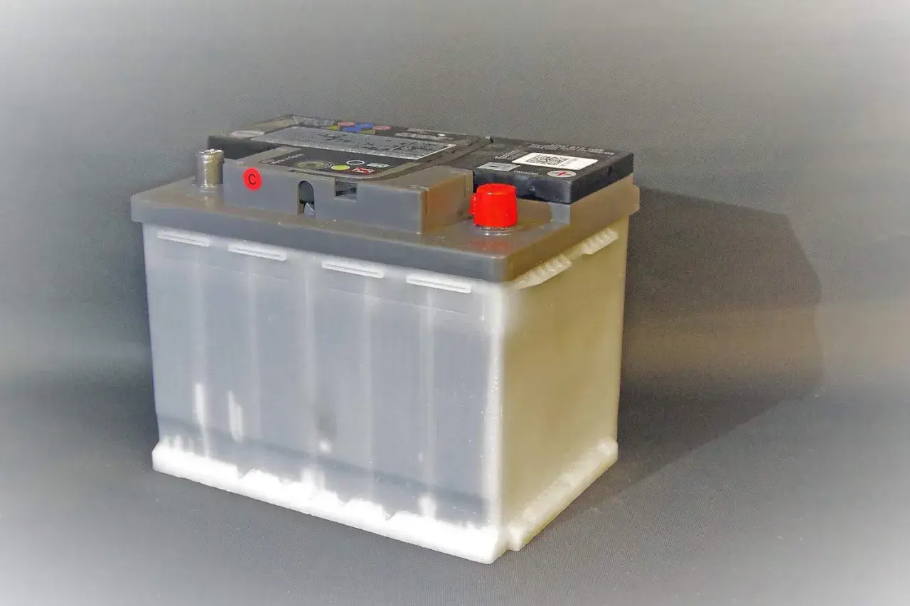 Autobatterie auf grauem Hintergrund. Beachten Sie die Lagerung von Autobatterien Vorschriften für sicheren Umgang.
