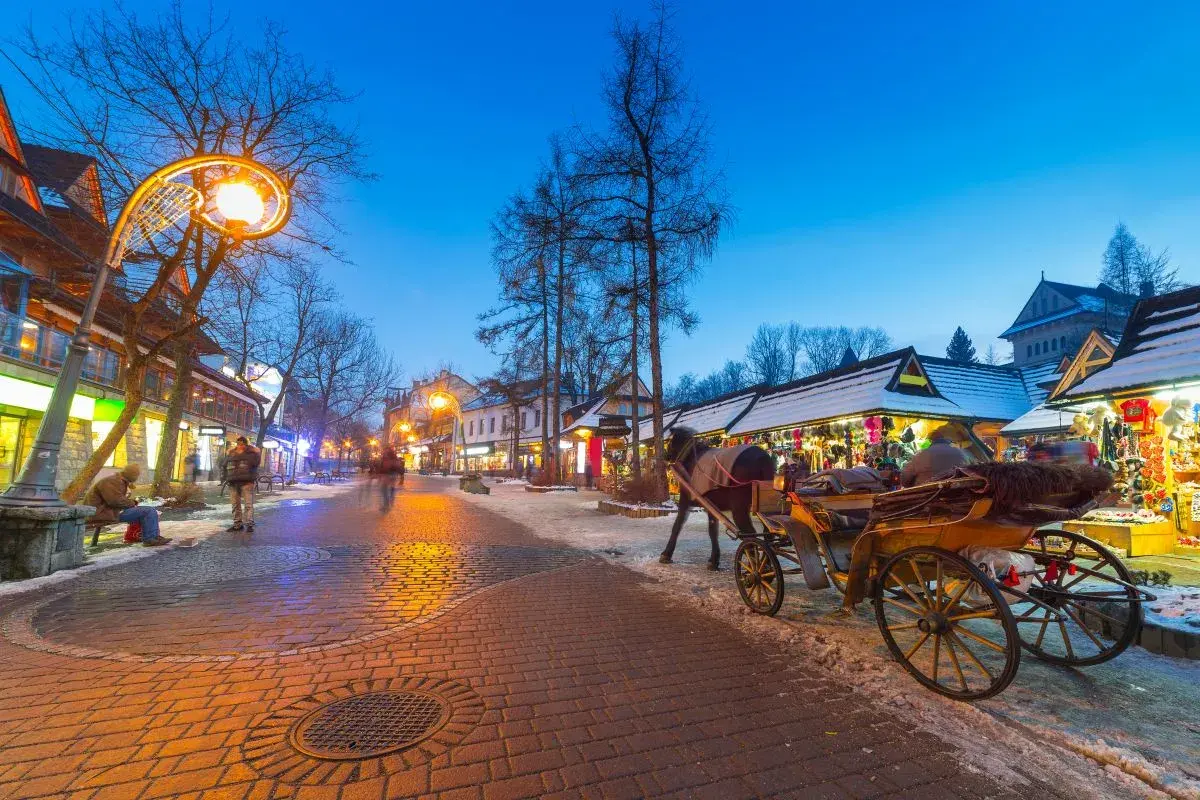 Wieczorny spacer po Krupówkach, gdzie zakopiańskie centrum kultury tętni życiem. Konny zaprzęg i oświetlone kramy tworzą magiczny klimat.