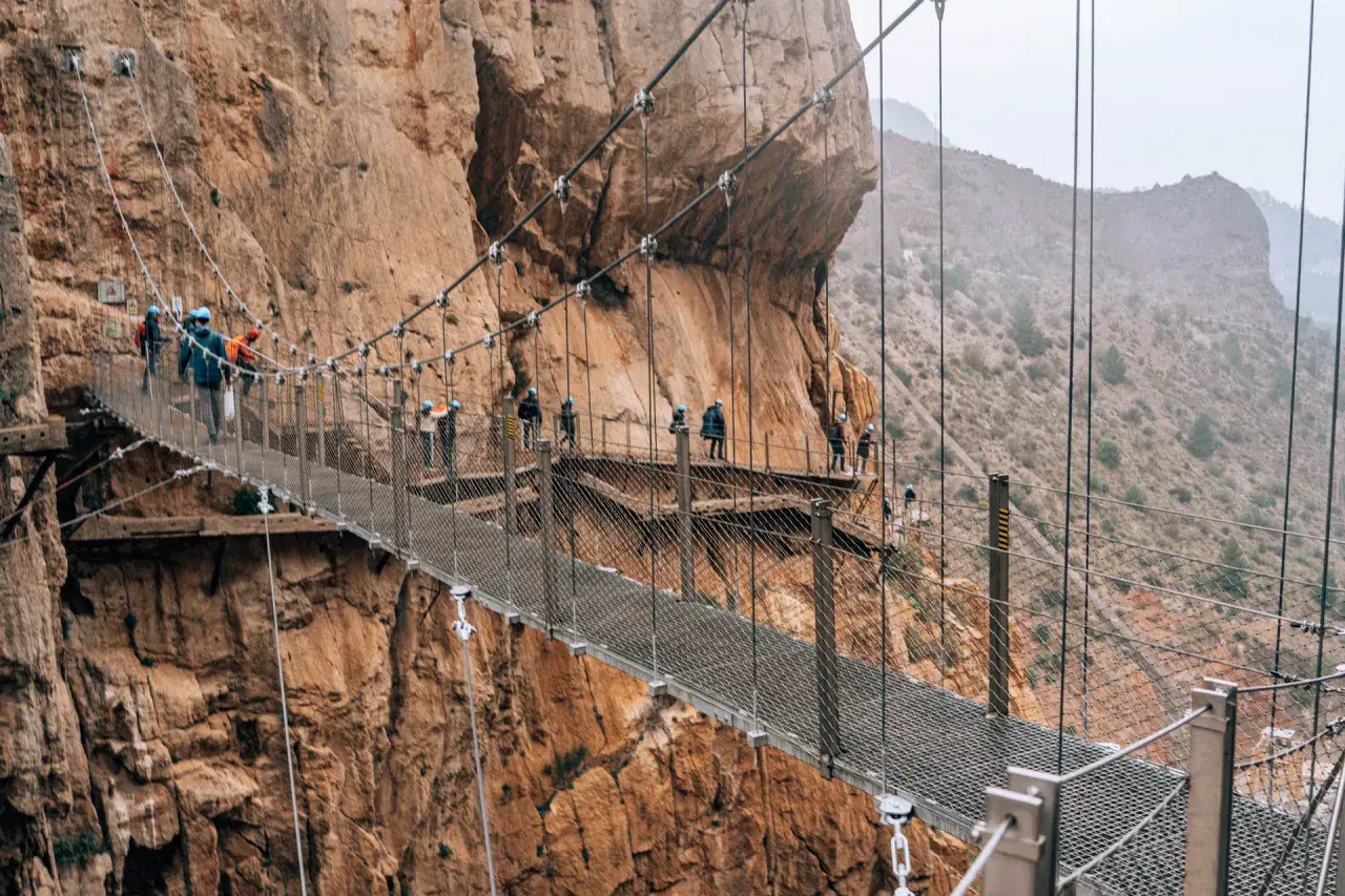 Spacer po Caminito del Rey z dzieckiem. Wąska ścieżka zawieszona nad przepaścią, otoczona skalnymi ścianami.