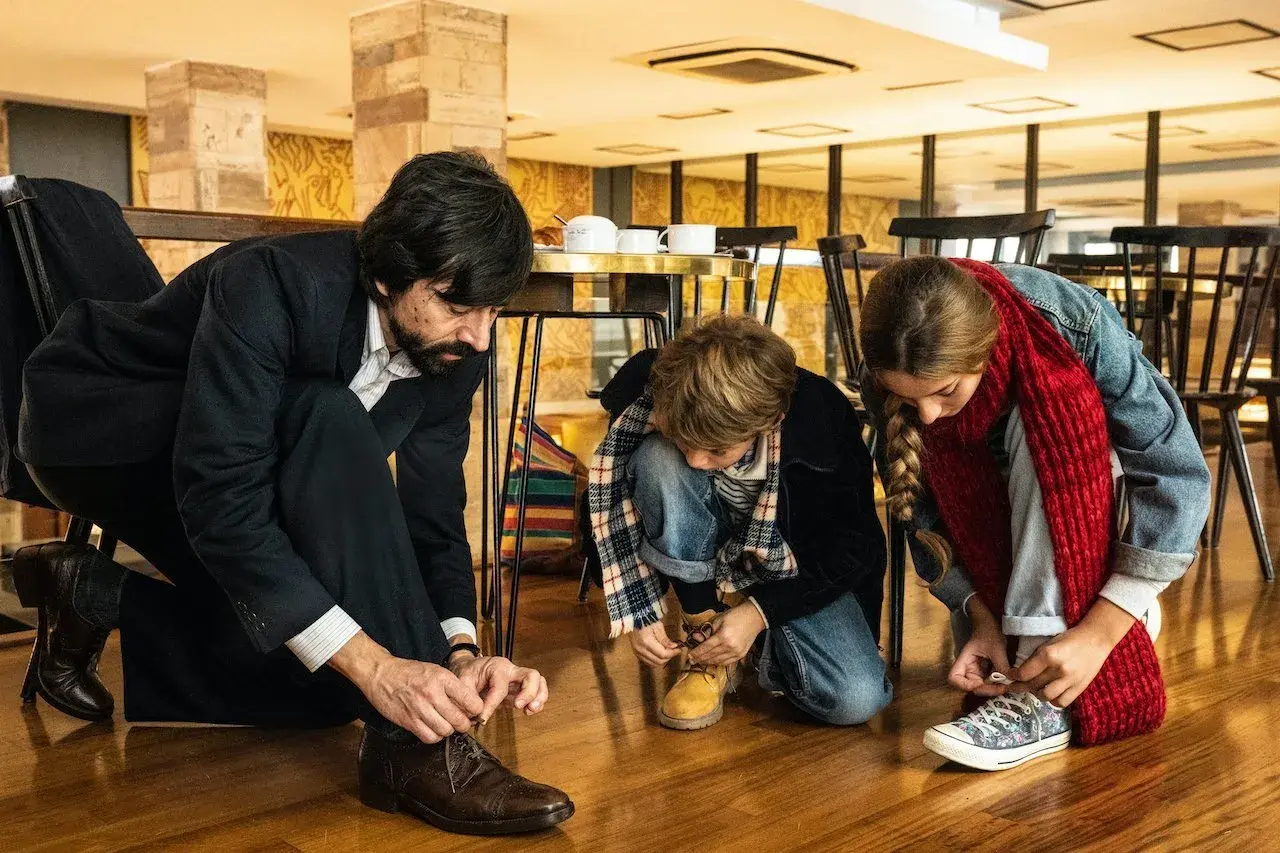 Padre e figli si allacciano le scarpe, un momento di vita quotidiana che merita recensioni positive per la sua semplicità.
