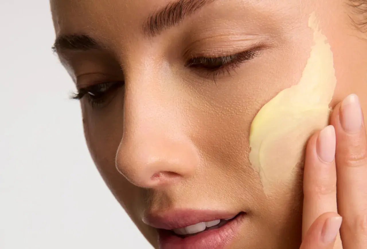 Application d'une crème riche en céramides pour une peau éclatante. Les doigts doux étalent la texture onctueuse.