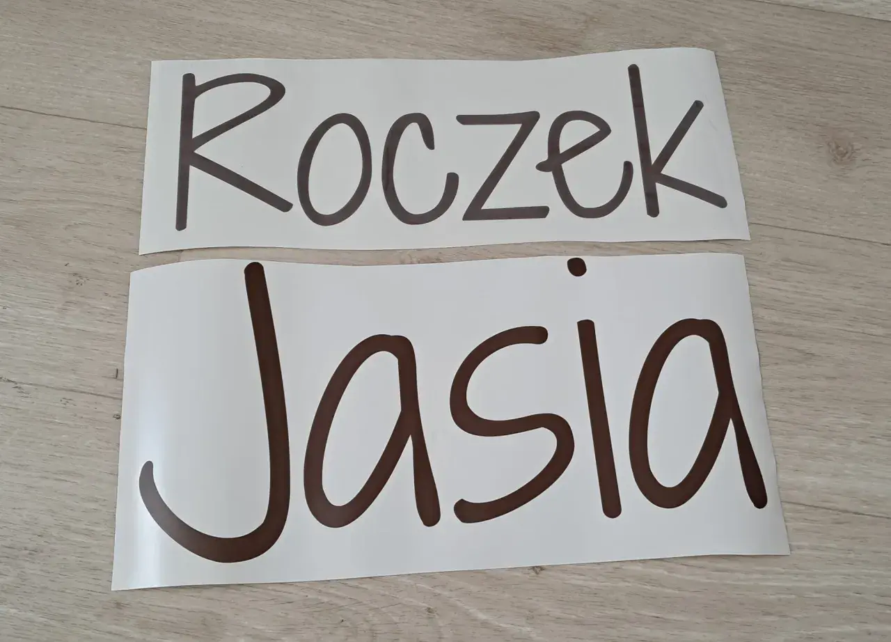 Napis "Roczek Jasia" na białych arkuszach, gotowy do dekoracji przyjęcia.