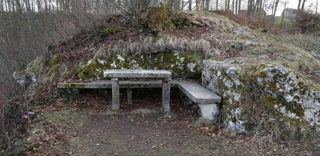 Ein Steintisch und Bänke laden zum Verweilen ein, nahe der ruine Herwartstein. Moosbewachsene Felsen und kahle Äste umgeben die Stelle.