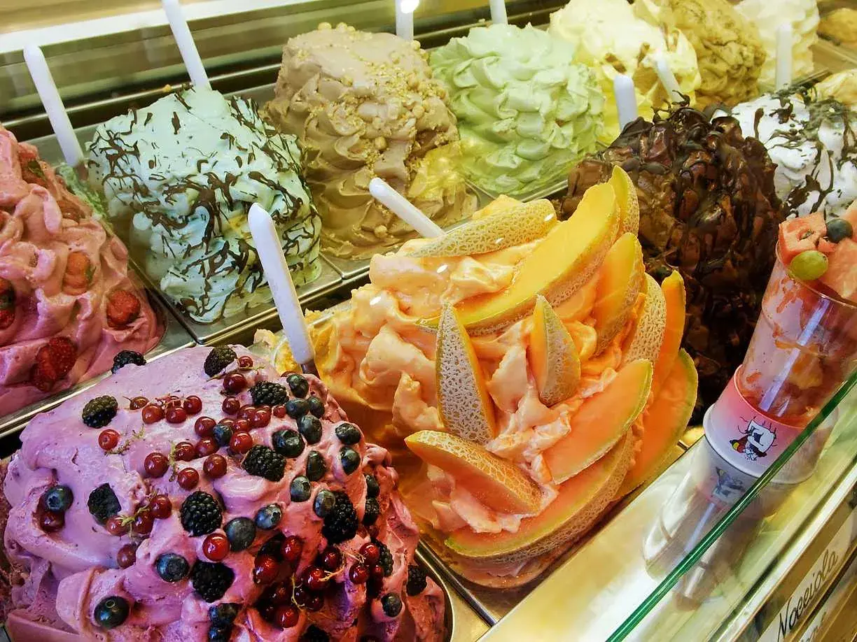 En display med olika sorters italiensk glass, inklusive bär, melon och choklad.