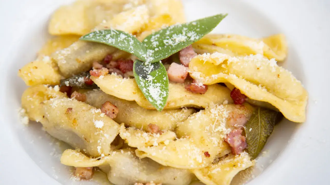 Un piatto di casoncelli alla bergamasca, ripieni e conditi con burro, salvia e pancetta croccante, spolverati di parmigiano.