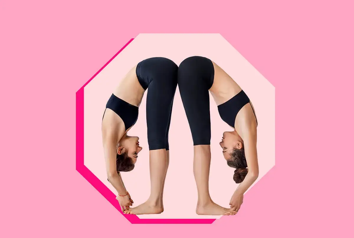 Due donne in posa yoga Uttanasana, schiena contro schiena, con le teste rivolte verso il basso.