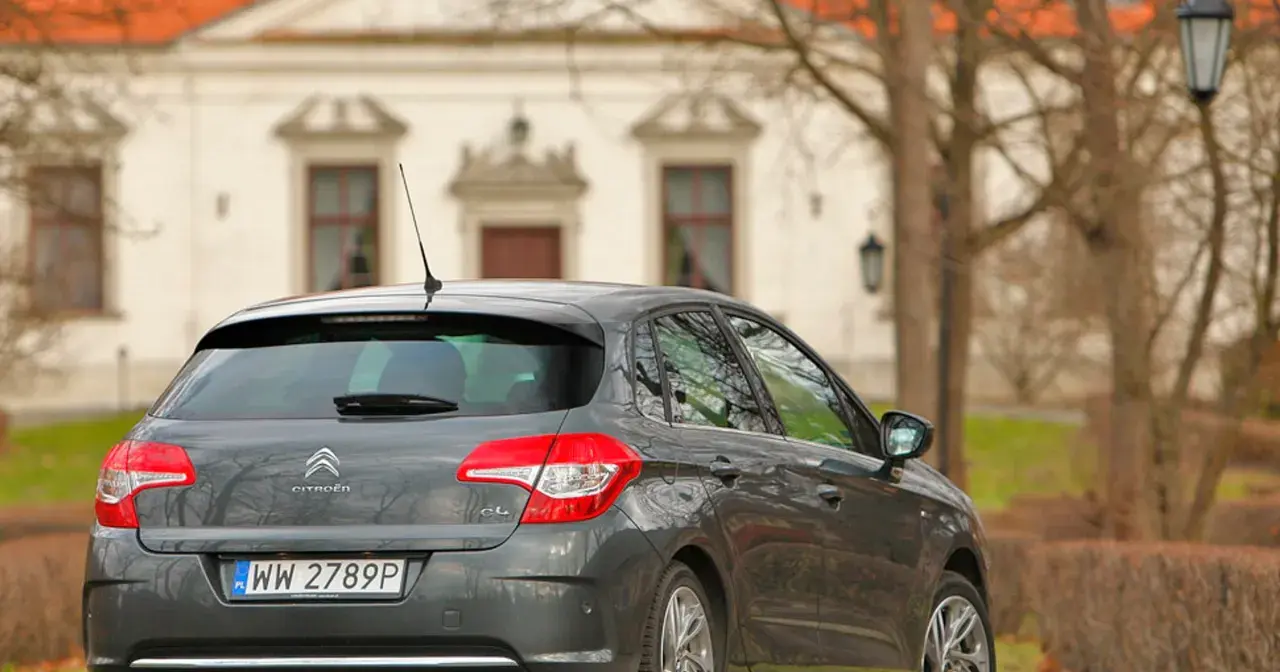 Szary Citroen C4 1.6 HDi zaparkowany przed zabytkowym budynkiem.