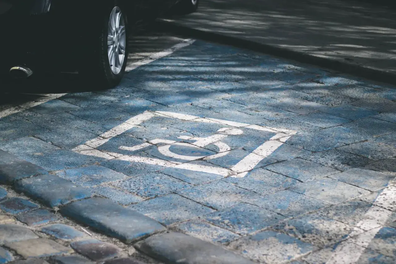 Symbol osoby na wózku inwalidzkim na niebieskim tle, wyznaczający miejsce parkingowe. Podział miejsca parkingowego we wspólnocie mieszkaniowej.