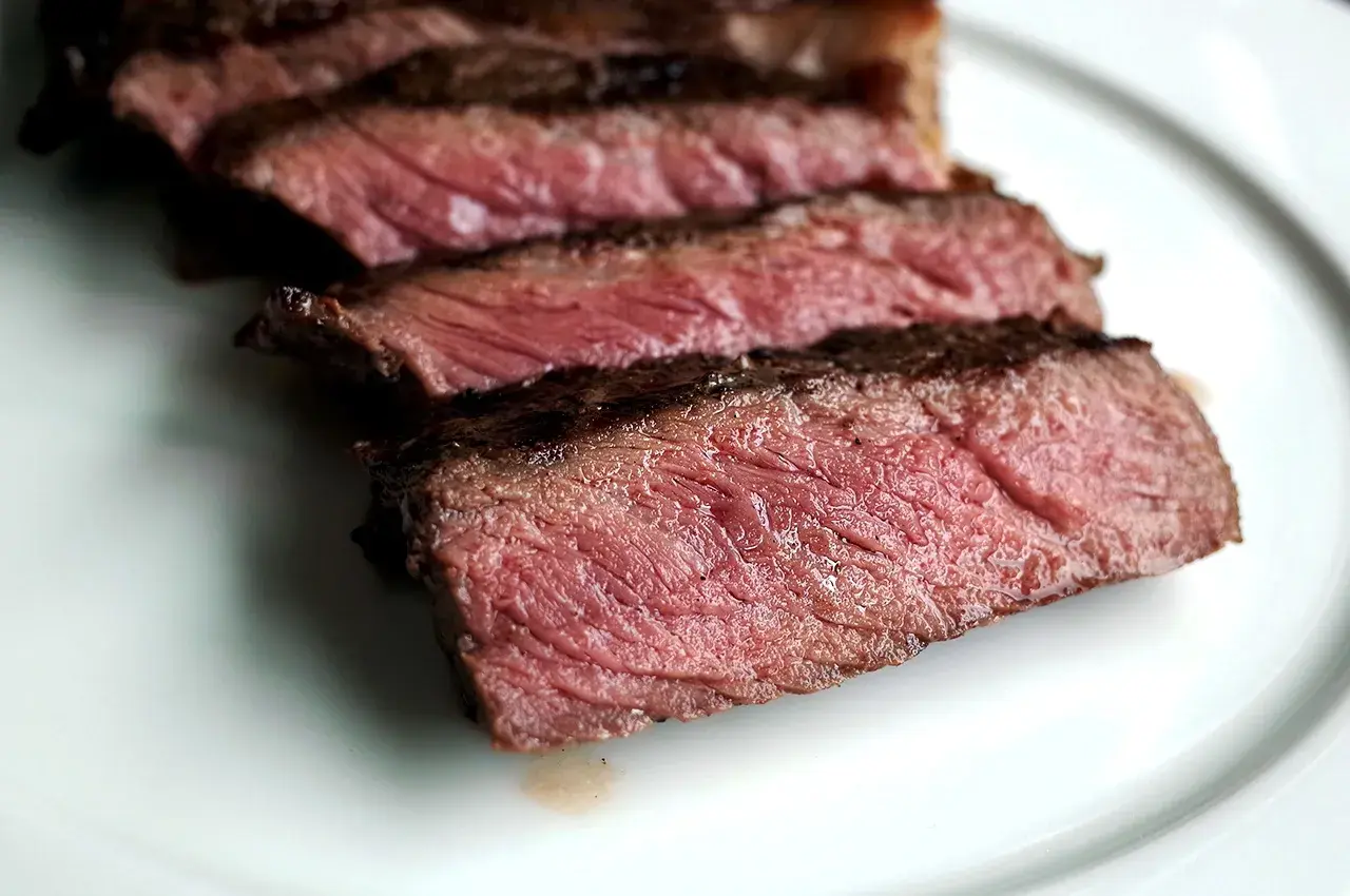Tranches de bœuf bleu blanc belge, juteuses et saignantes, sur une assiette blanche.