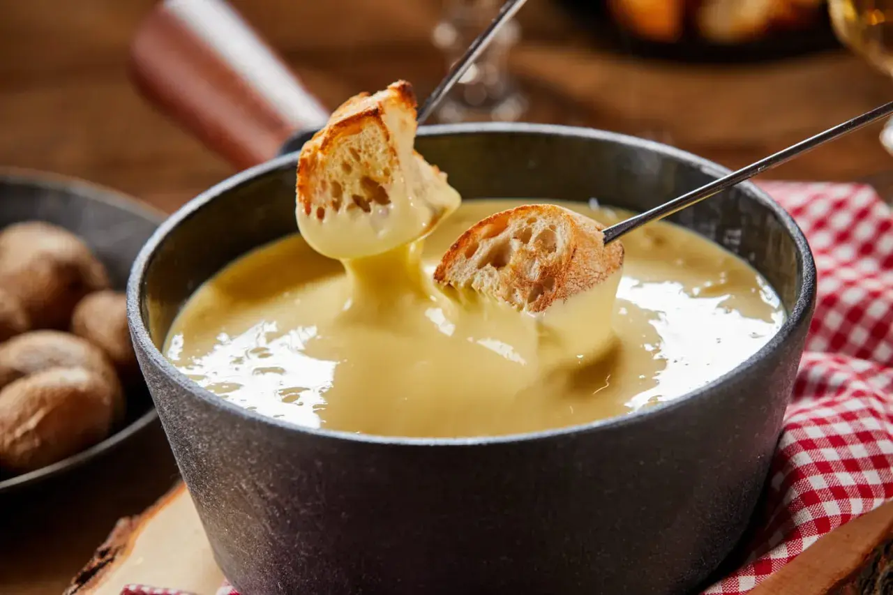 Des morceaux de pain trempés dans une fondue au fromage crémeuse. Un délice de pain fondue à partager.