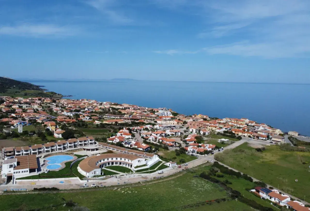 Widok z lotu ptaka na kurort GH Santina Resort z basenem i budynkami, nad morzem na Sardynii.