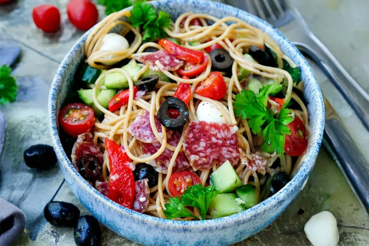 Spaghetti-Salat mit Salami, Tomaten, Oliven und Mozzarella. Ein einfach und schnell zubereitetes Gericht, perfekt für heiße Tage.