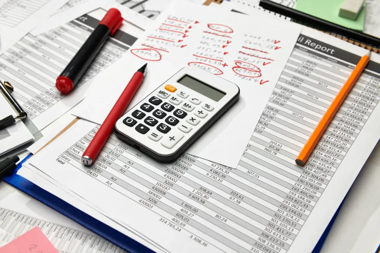 Calculatrice, stylos et feuilles de calcul. Préparation des comptes pour la taxe sur les salaires 2024.