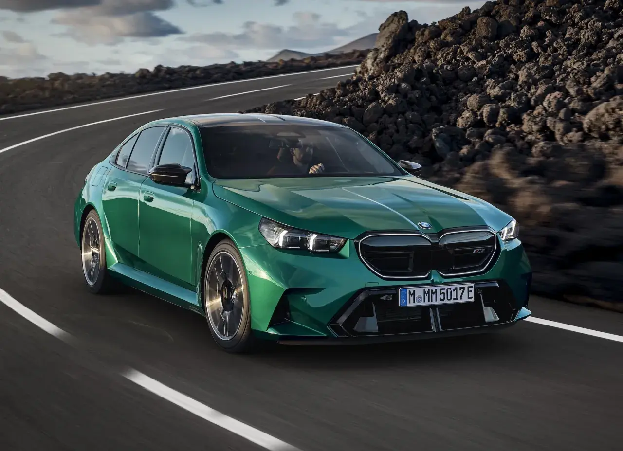 Zielone m5 bmw pędzi po krętej drodze wśród skalistych krajobrazów.