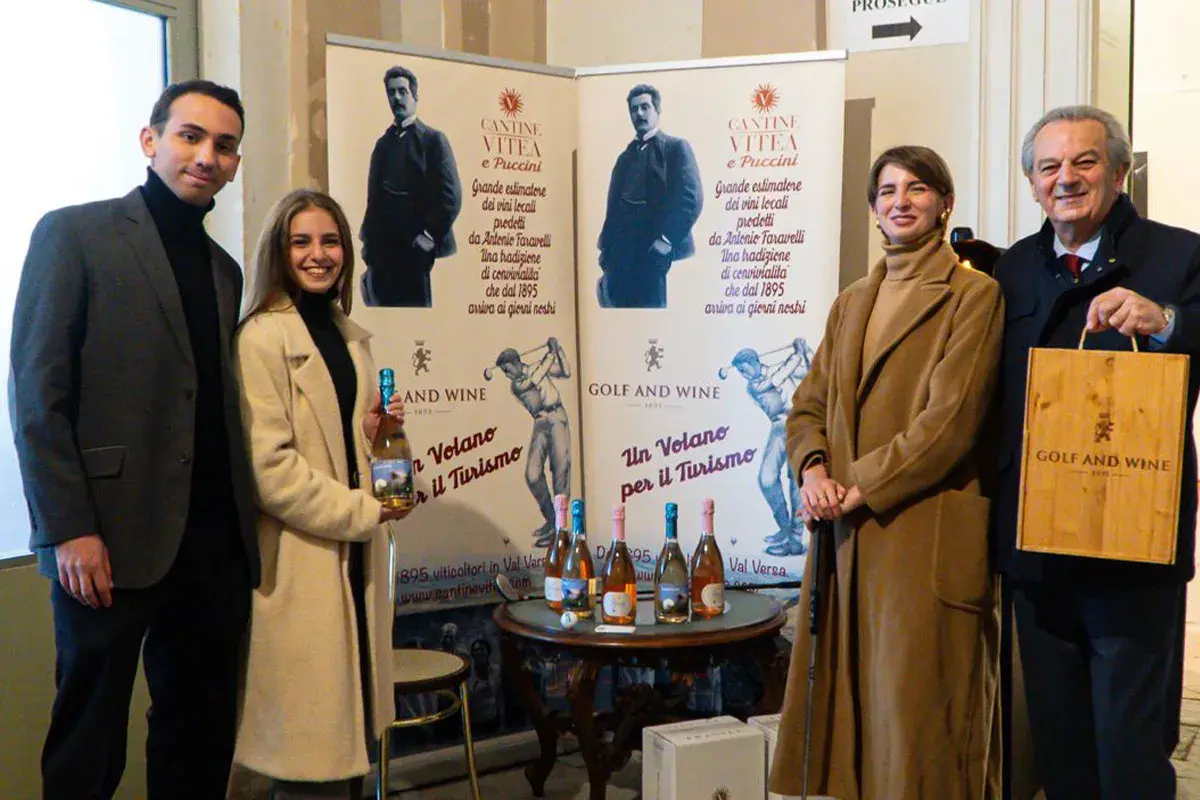 Antonio Faravelli, un nome legato alla tradizione vinicola. Quattro persone sorridono davanti a banner che celebrano la storia di Cantine Vitea e Puccini.