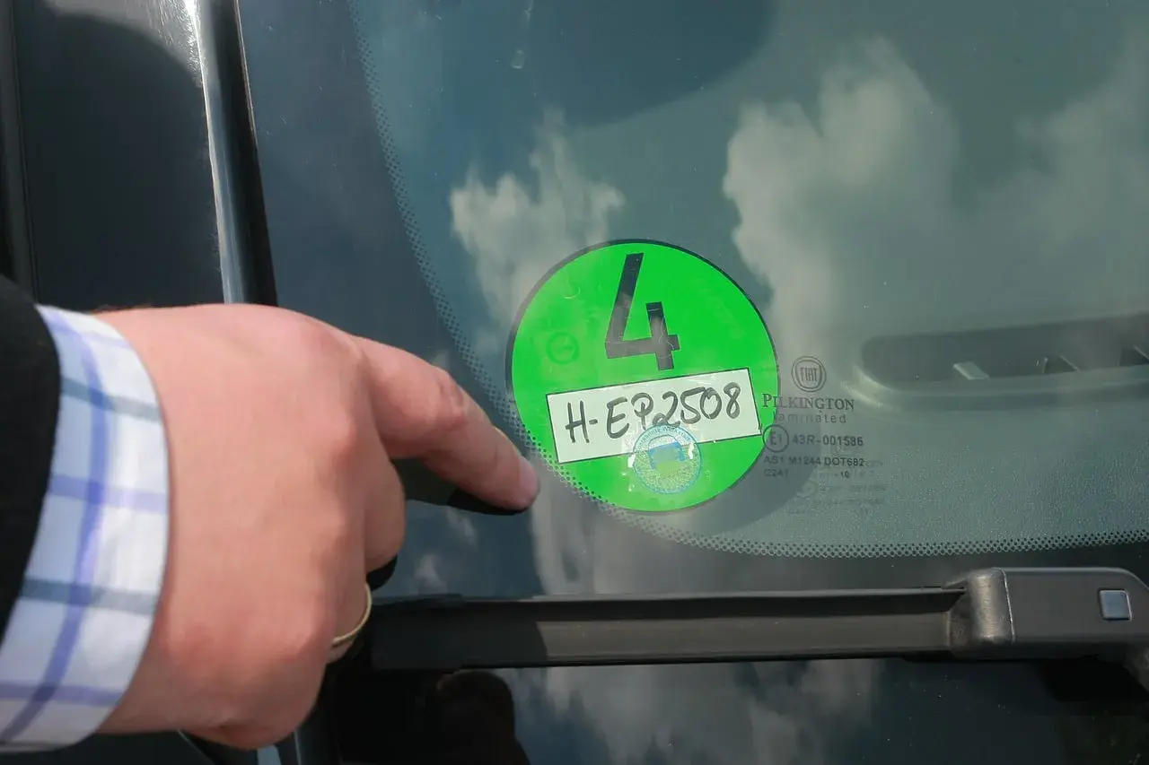 Palec wskazuje na zieloną winietę z numerem 4 i rejestracją H-EP2508, naklejoną na przedniej szybie samochodu w Niemczech.