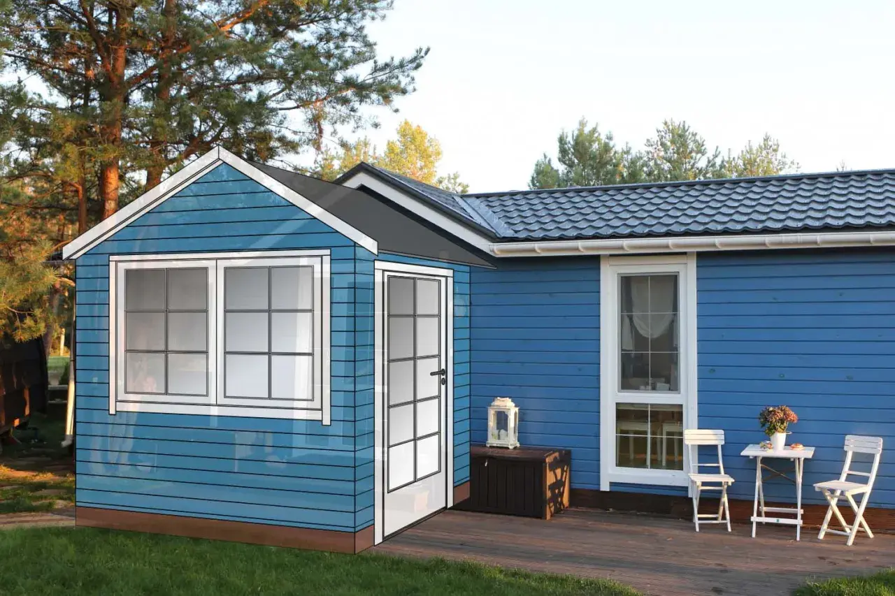 En blå stuga med vita fönster och dörr, redo att bygga farstukvist. En liten uteplats med bord och stolar.