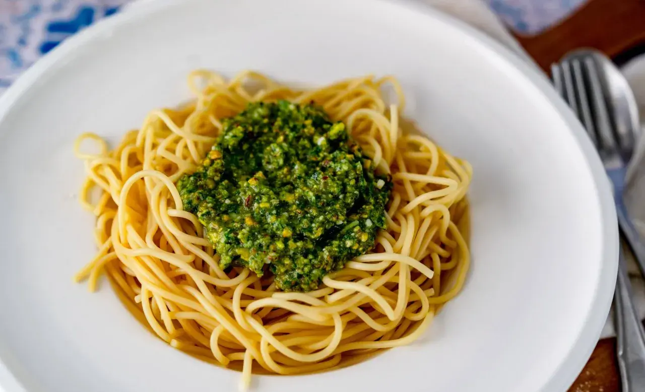 Spaghetti mit einem Berg von leckerem Pistazien Pesto, garniert mit gehackten Pistazien.