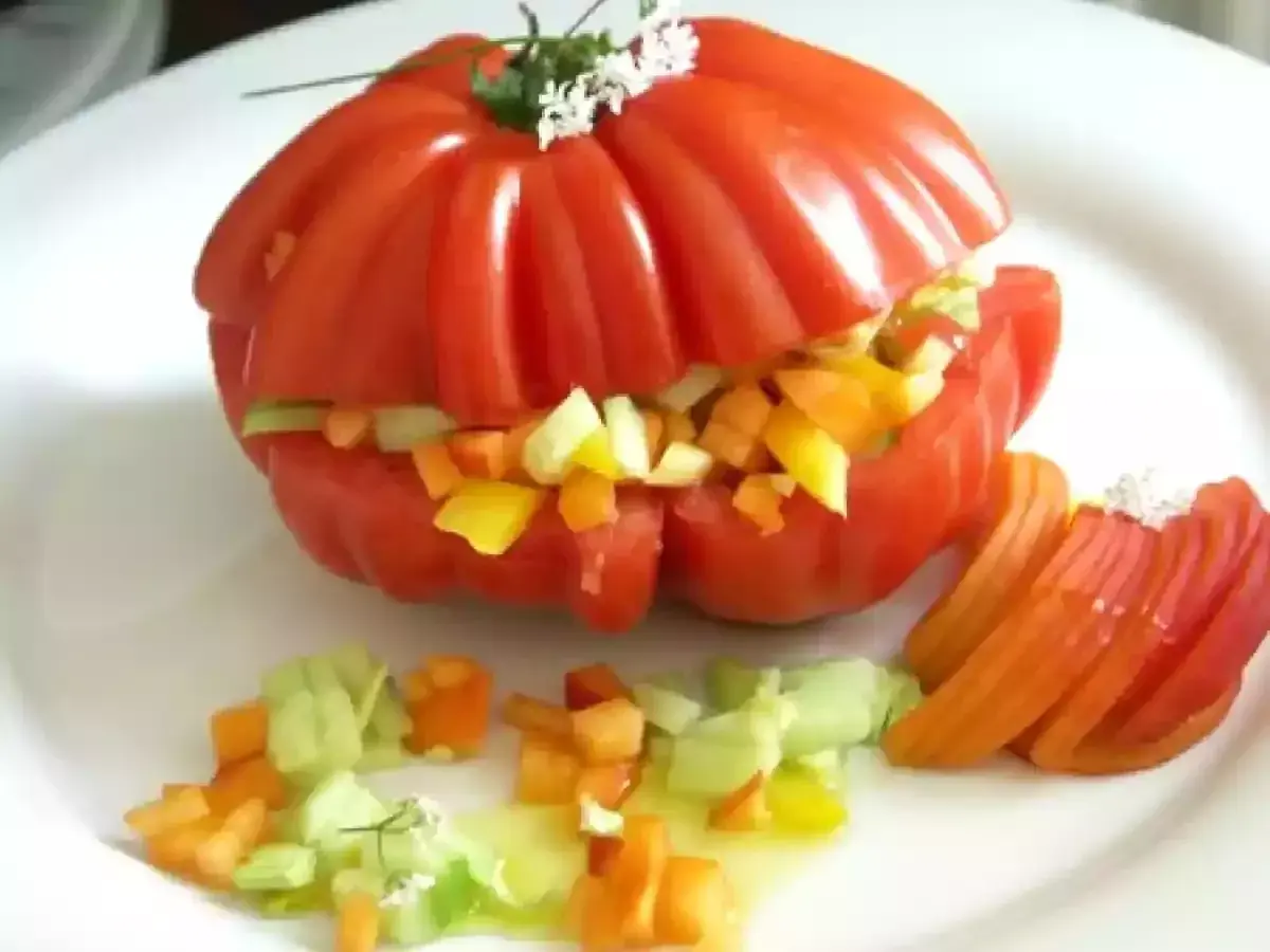 Un tomate cœur de bœuf farci de légumes croquants, servi avec des quartiers de tomate et une vinaigrette légère. Un délice estival !