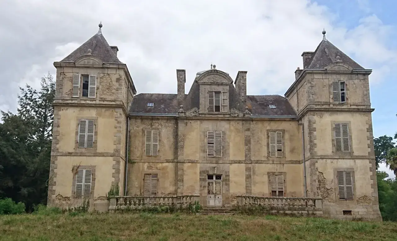 Vaste manoir abandonné en Bretagne, aux façades décrépites et aux volets clos, témoignant d'une histoire oubliée.