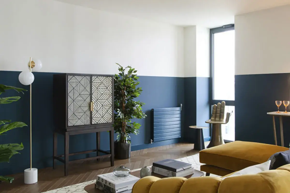 Soggiorno moderno con pareti bicolore blu e bianche, un mobile etnico e un divano giallo ocra. Idee pareti colorate particolari per un look audace.