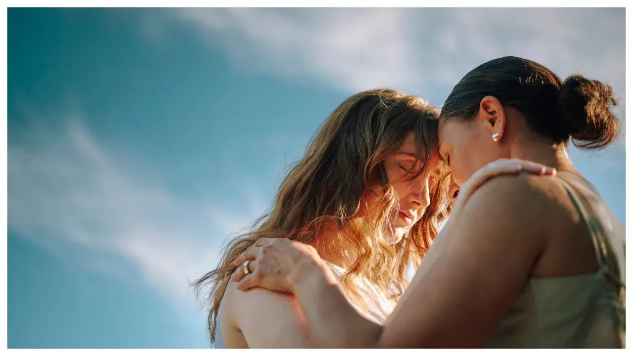 Due donne si abbracciano con dolcezza, un'immagine che evoca il vero amore platonico, significato di profonda connessione spirituale sotto un cielo azzurro.