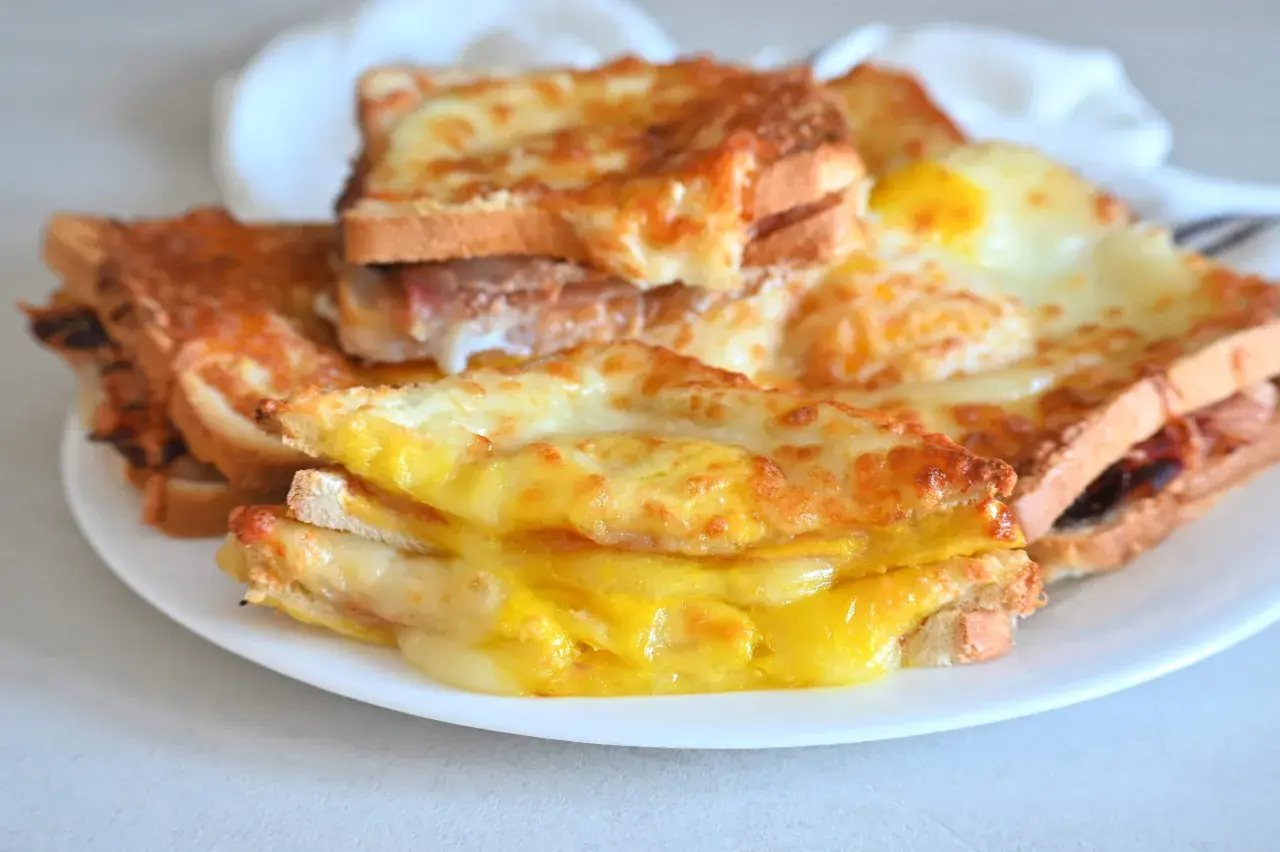 Toast filanti e dorati, preparati nella friggitrice ad aria, con formaggio fuso e un uovo.