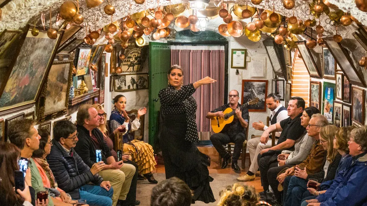 Una bailaora de flamenco, con un guitarrista y público, en un local decorado con cobre. ¡Gracias en flamenco!