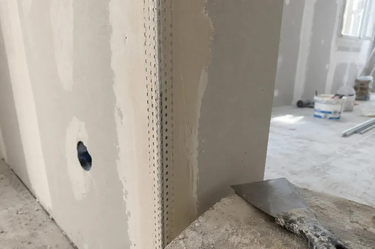 Angoli in cartongesso pronti per la stuccatura. Un angolo è rinforzato con nastro metallico, mentre l'altro è già parzialmente stuccato.
