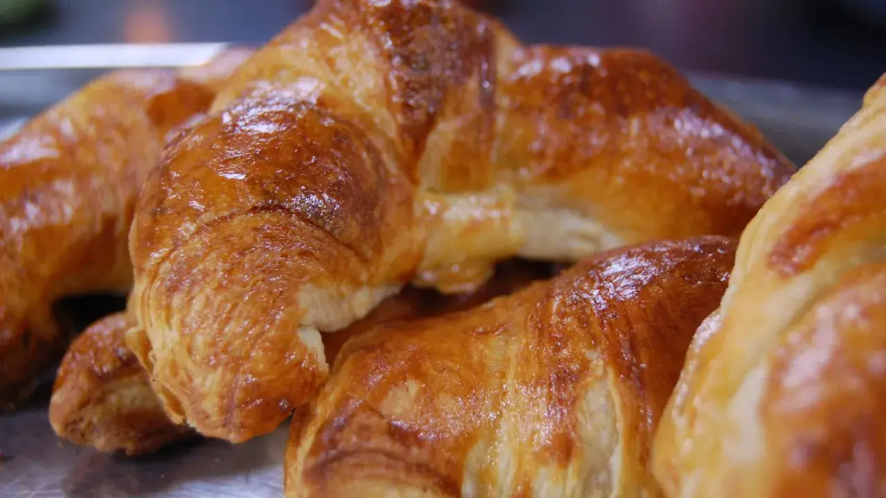 Nybakade, gyllene croissanter som ser ut att vara perfekt att baka.