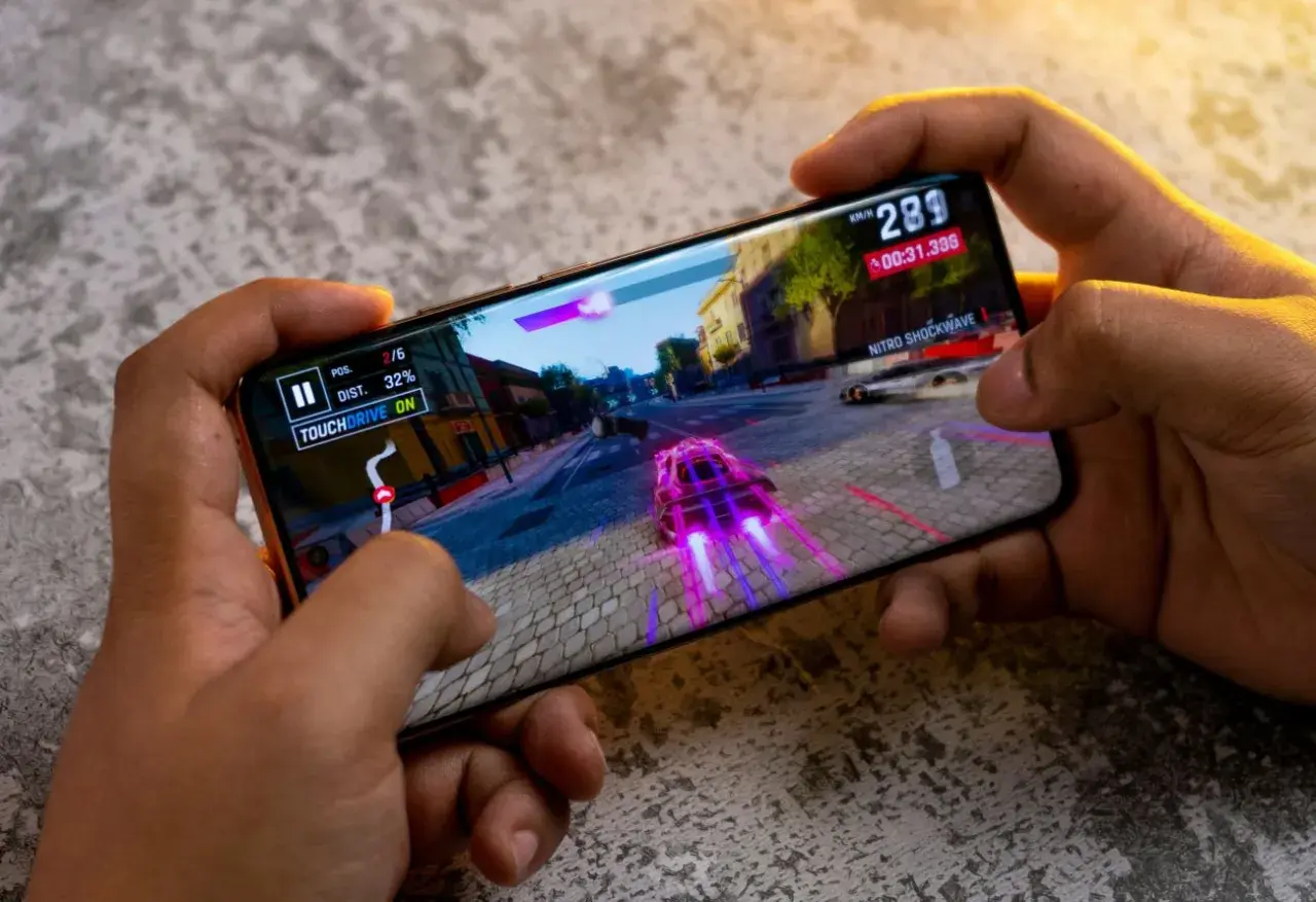 Ręce trzymają smartfon, na którym gra wyścigowa. Idealny telefon do 2500 zł poradzi sobie z taką grafiką.