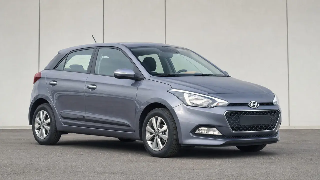 Szary Hyundai i20 z włączonymi światłami pozycyjnymi na tle jasnej ściany.