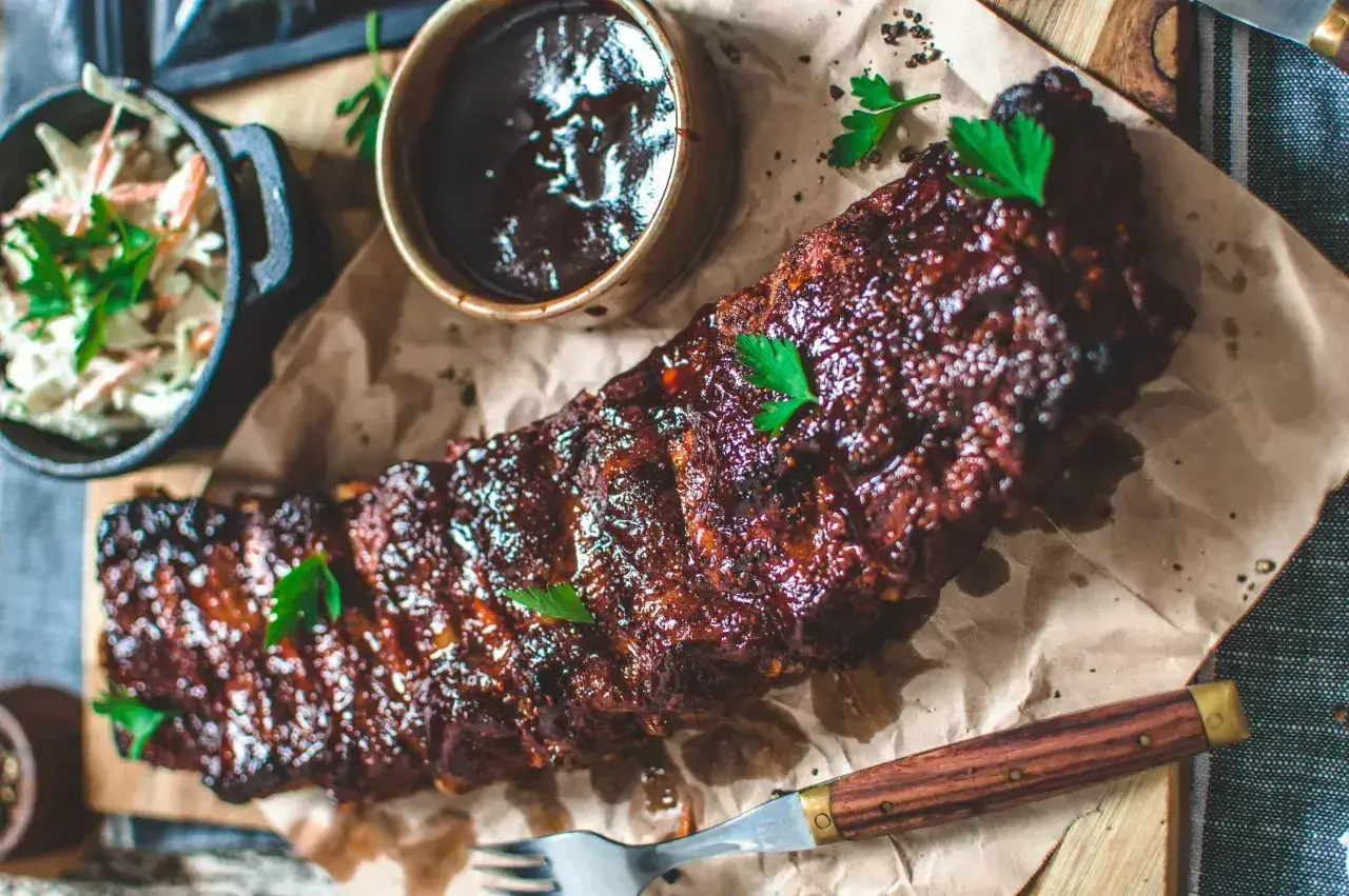 Saftiga ribs på grillen, glaserade och redo att avnjutas med en krispig coleslaw och en skål med BBQ-sås.