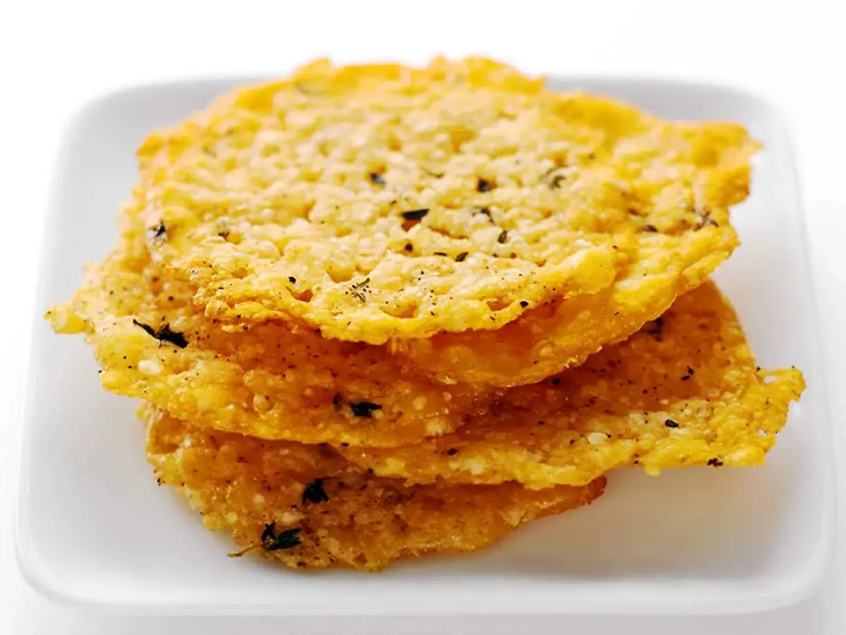 Krispiga, gyllene pasta chips med örter och peppar staplade på en vit tallrik. Perfekt som tilltugg!