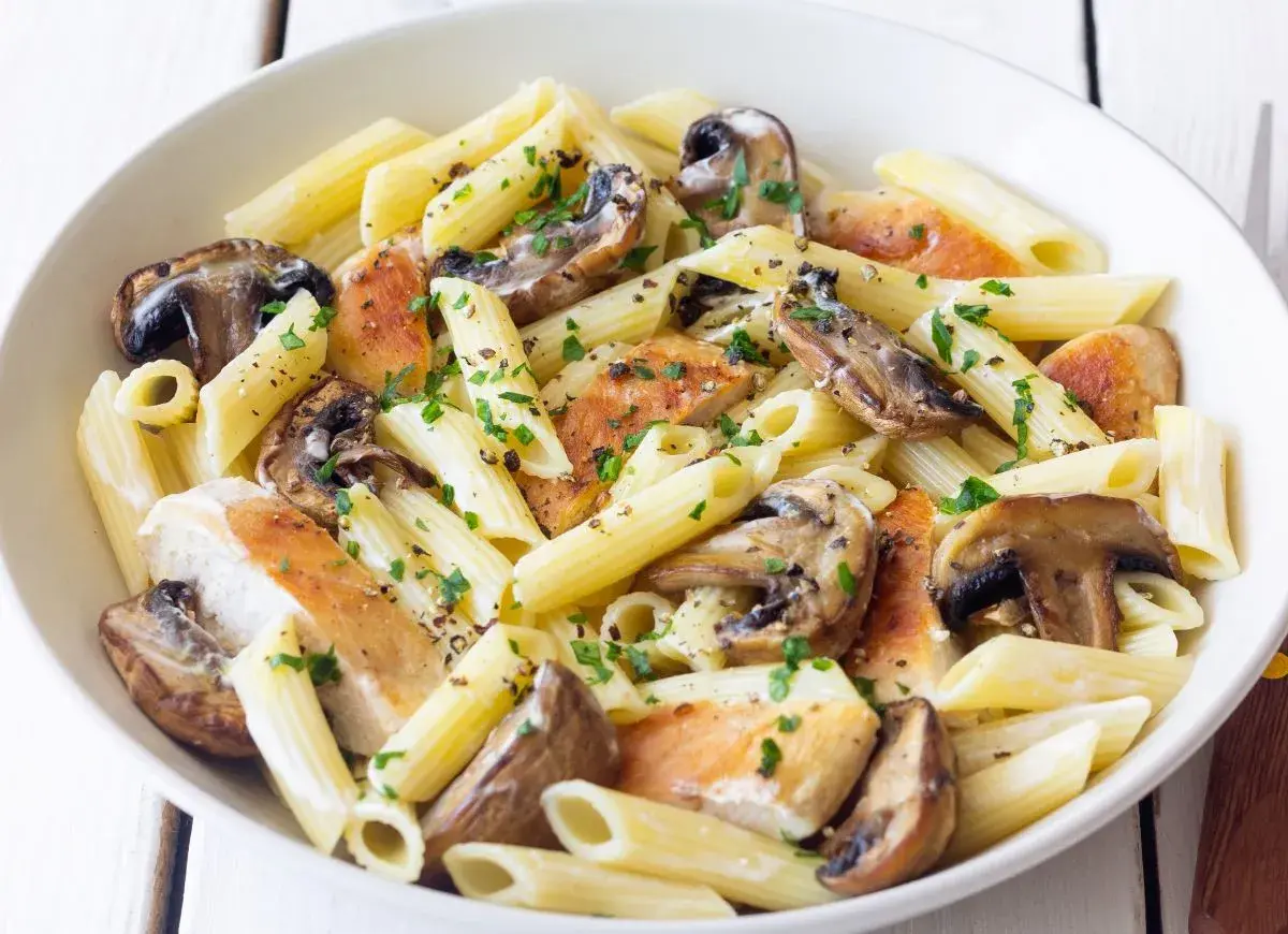 Penne z kurczakiem i pieczarkami, posypane natką pietruszki i pieprzem. Pyszne danie, które z pewnością zadowoli każdego miłośnika makaronu z kurczakiem.