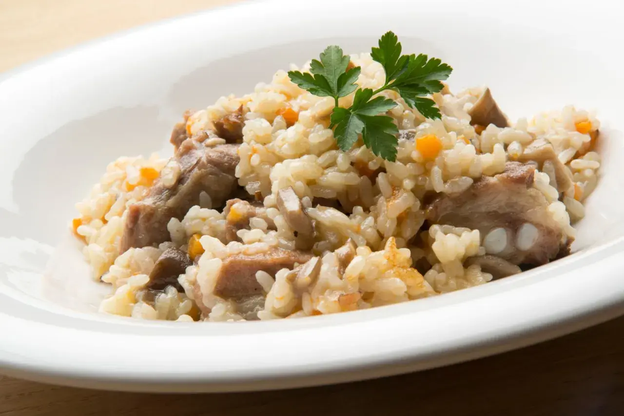 Delicioso arroz con champiñones y trozos de carne, adornado con perejil fresco.