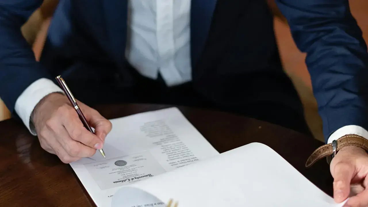Persona firma un contrato laboral con un bolígrafo de oro.