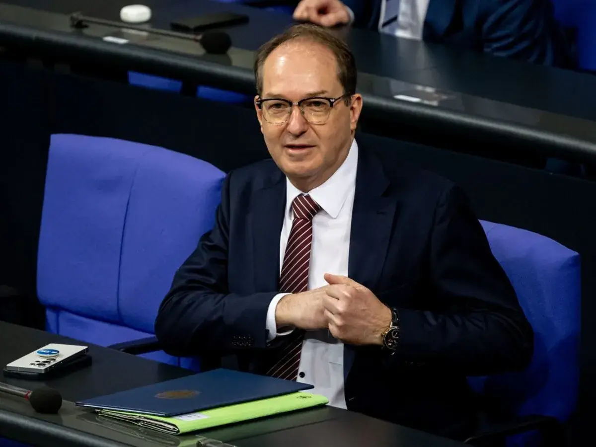 Ein Mann mit Brille und Krawatte sitzt im Bundestag. Er wirkt nachdenklich, während er seine Hände faltet. Viele Bundestagsabgeordnete sind Beamte.