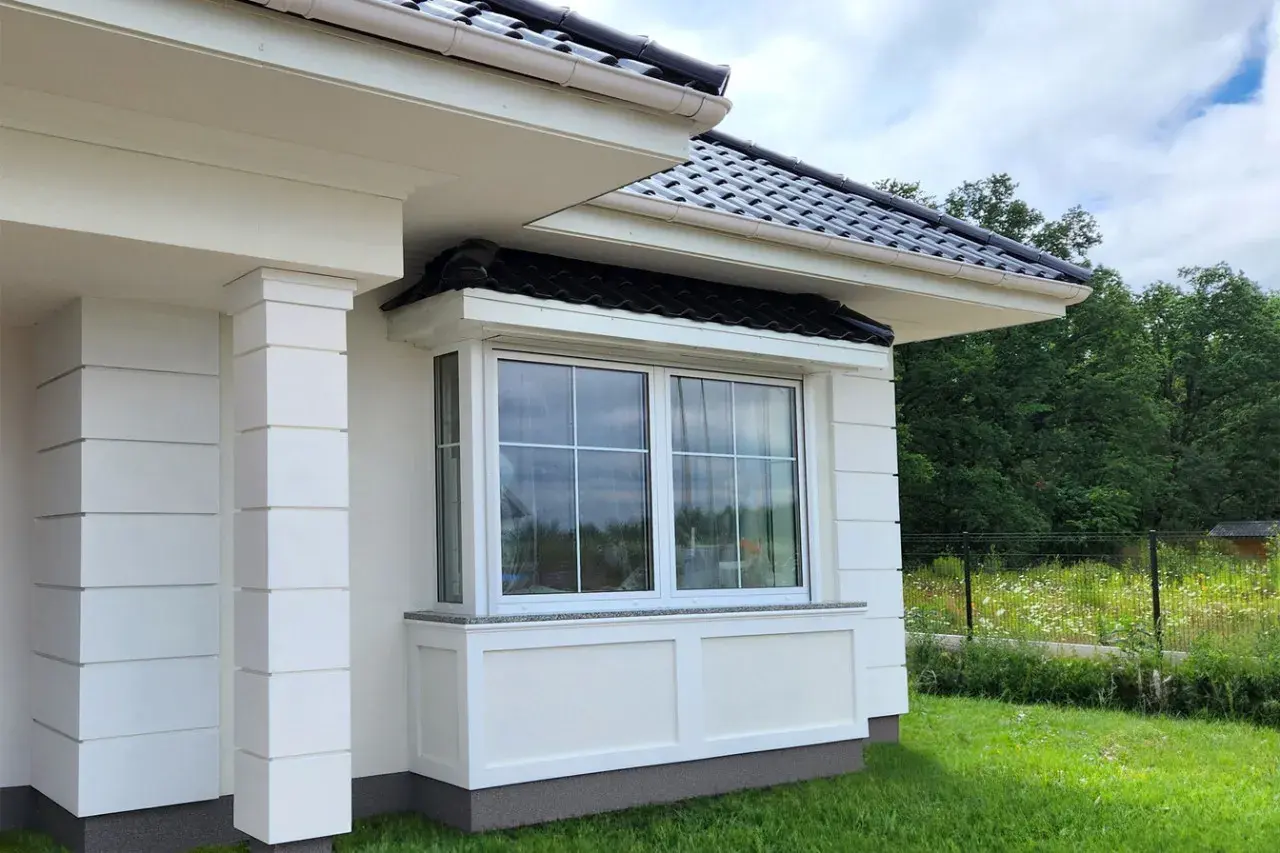 Frisch gestrichene weiße Fassade mit Fenster und Säulen.