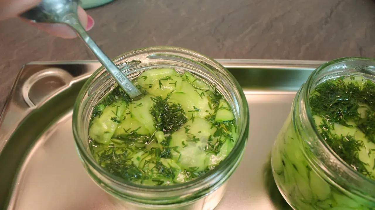 Ein Glas Gurkensalat mit Dill wird mit einem Löffel vorbereitet, bereit zum Gurkensalat einkochen.