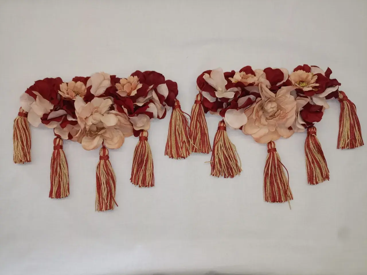Dos adornos florales con borlas rojas y doradas, perfectos para saber como hacer hombreras flamencas.