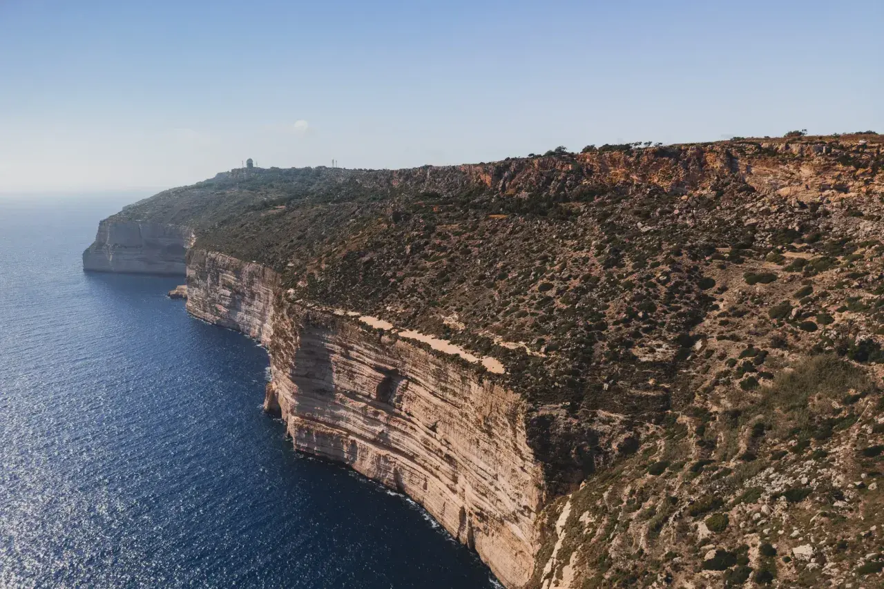Malta: klify nad turkusowym morzem, skaliste wybrzeże z roślinnością.