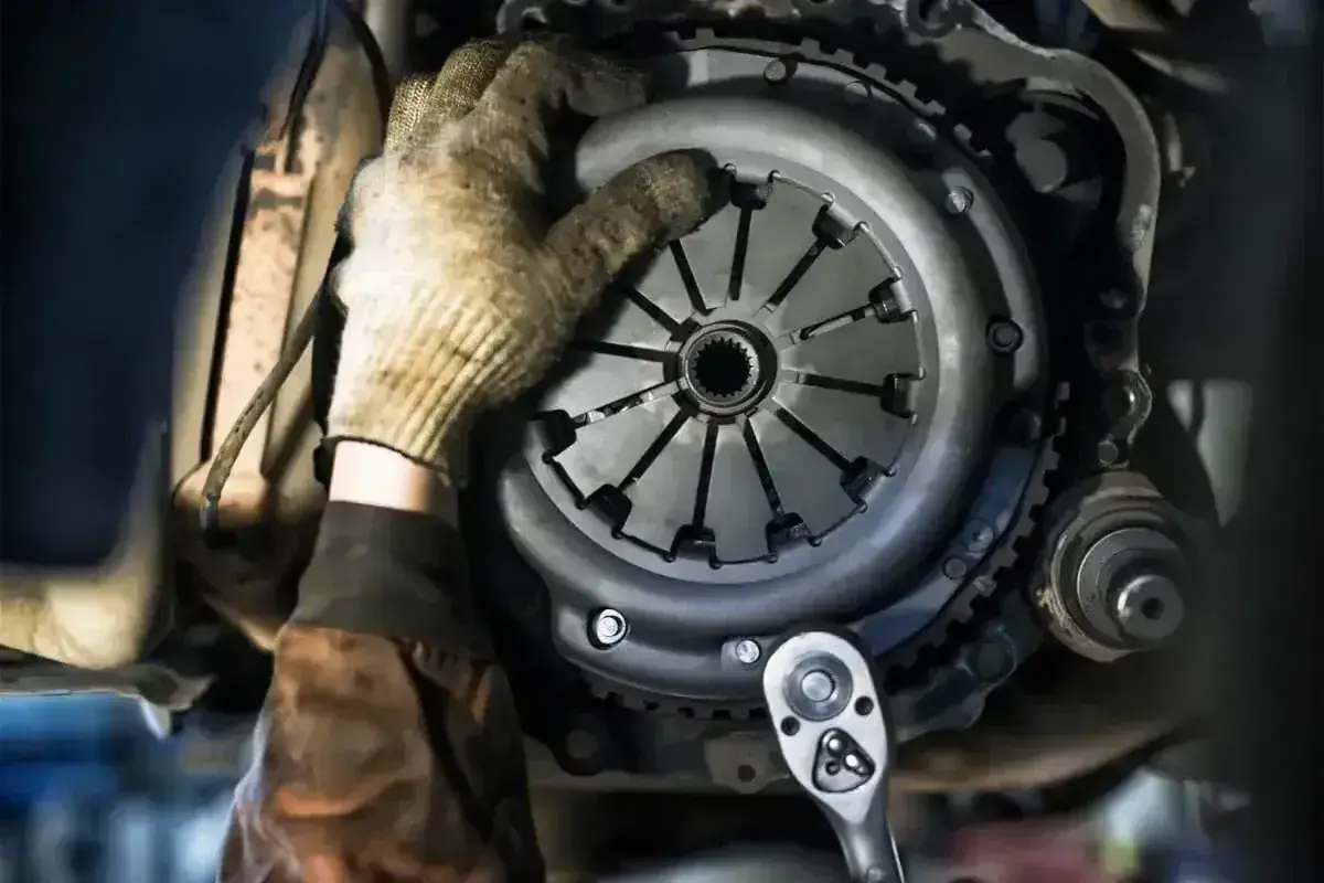 Mechanik w rękawicy próbuje zamontować tarczę sprzęgła. Ciezko wchodzi 1, ale z kluczem nasadowym praca pójdzie sprawniej.