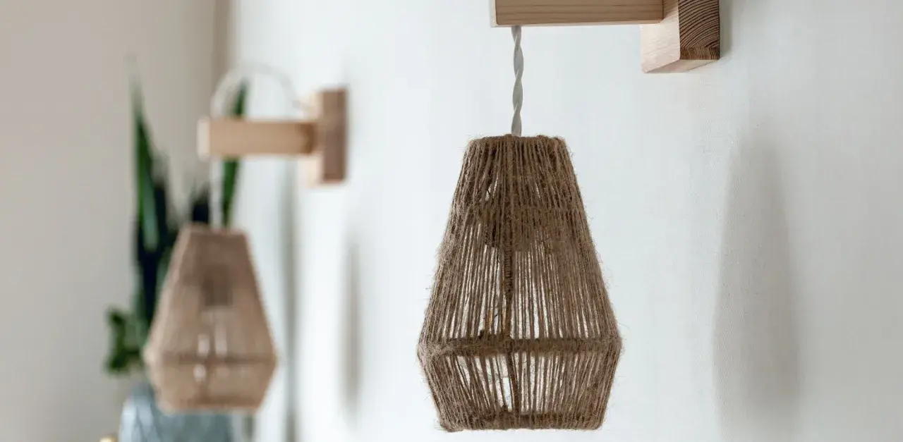 Dos lámparas de pared colgantes de cuerda natural, con soportes de madera, crean un ambiente rústico y acogedor.