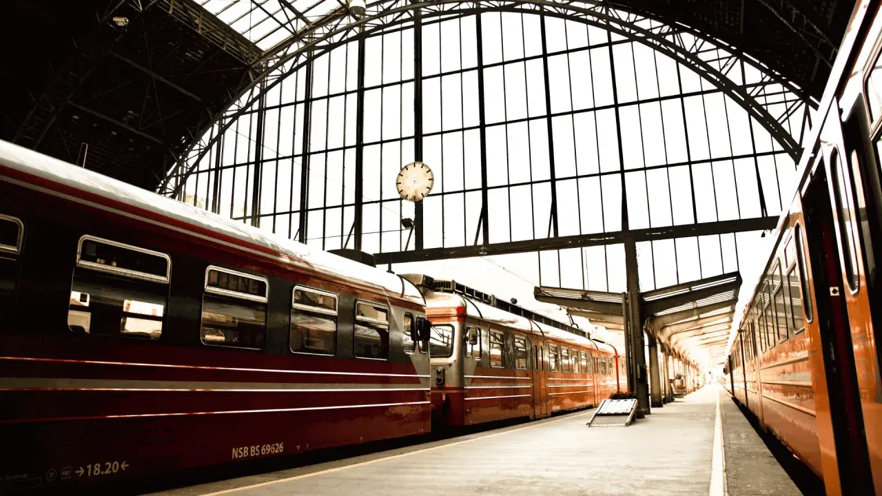 Czerwone pociągi na dworcu pod szklanym dachem. Zastanawiasz się, ile kosztuje pociąg do Berlina?