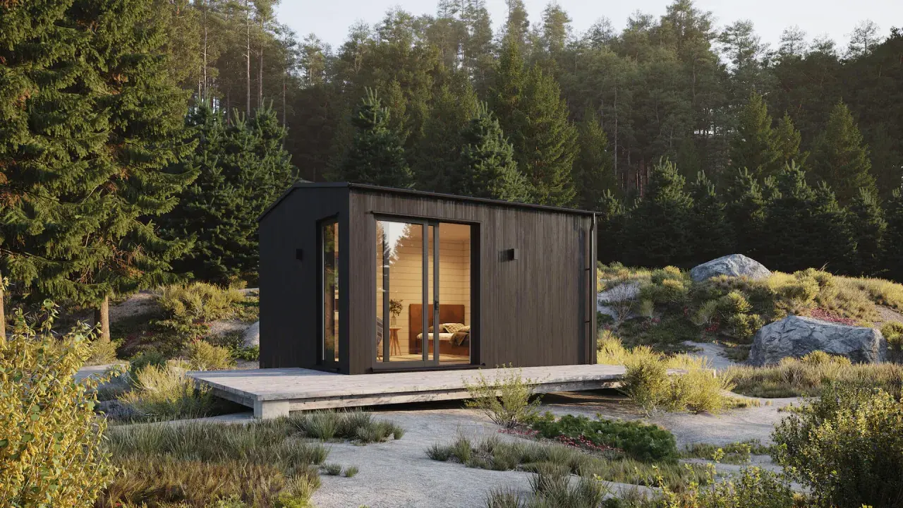 Modern friggebod med stora fönster, omgiven av skog och sten. Drömmen om att bygga friggebod blir verklighet.