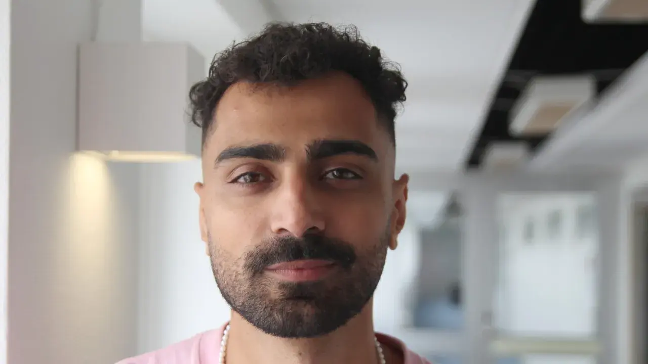 Alexander Abdallah, en ung man med lockigt mörkt hår och skägg, tittar rakt in i kameran.