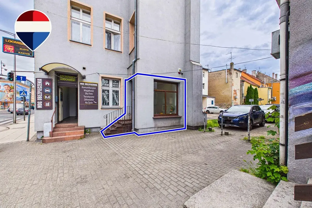 Budynek z wejściem do biura ubezpieczeń i oknem, zaznaczony niebieską ramką.