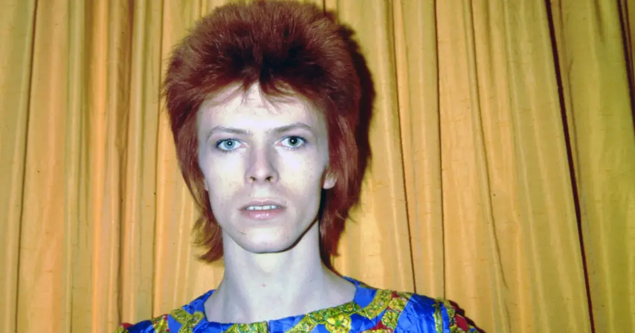 Ikoniczny David Bowie z burzą rudych włosów i niebieskimi oczami, w stroju przypominającym jego słynne kreacje. Jego muzyka, jak te utwory, wciąż inspiruje.
