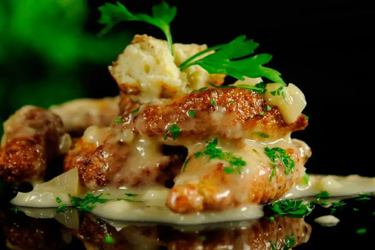 Deliciosas albóndigas de rape doradas, cubiertas con una cremosa salsa y perejil fresco. Un plato que invita a probar.
